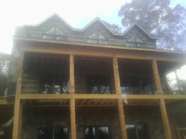 Dormers and porch framing on a large log home under construction — Roof Coating work by our crew in Cheswick