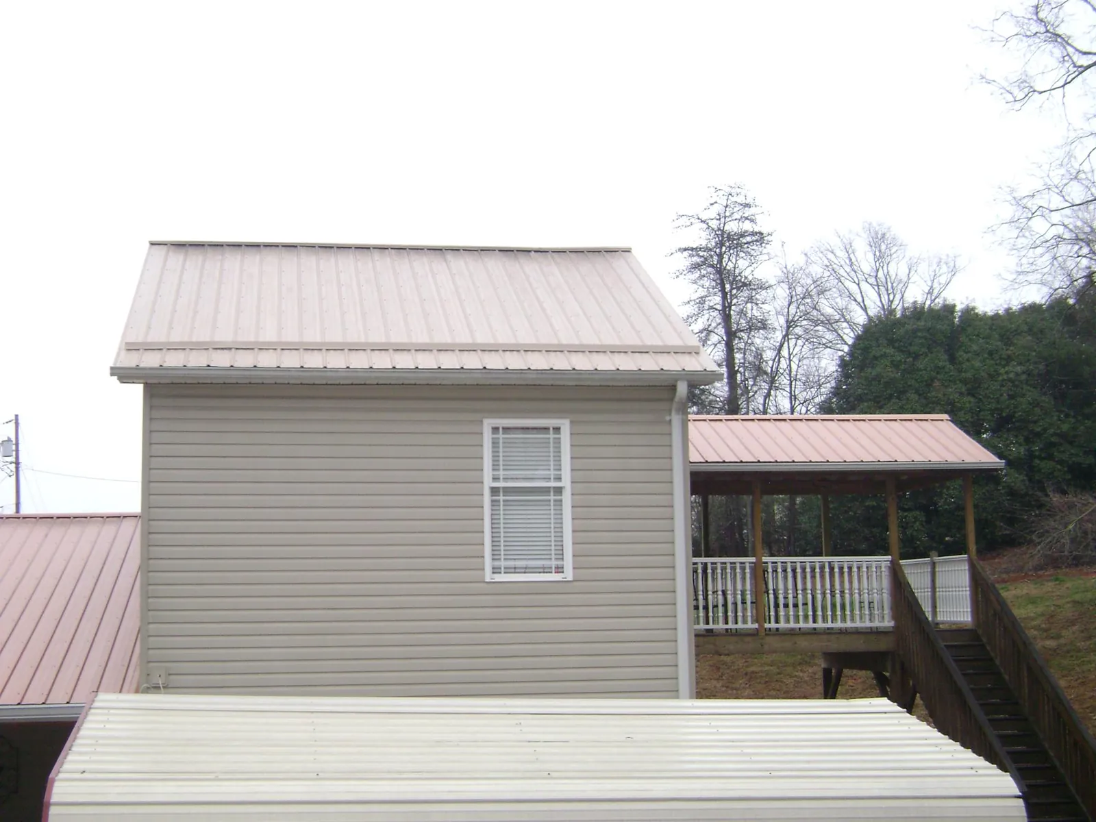 Tan metal roofs on a two story addition and attached porch, from a Roof Replacement job in Cheswick