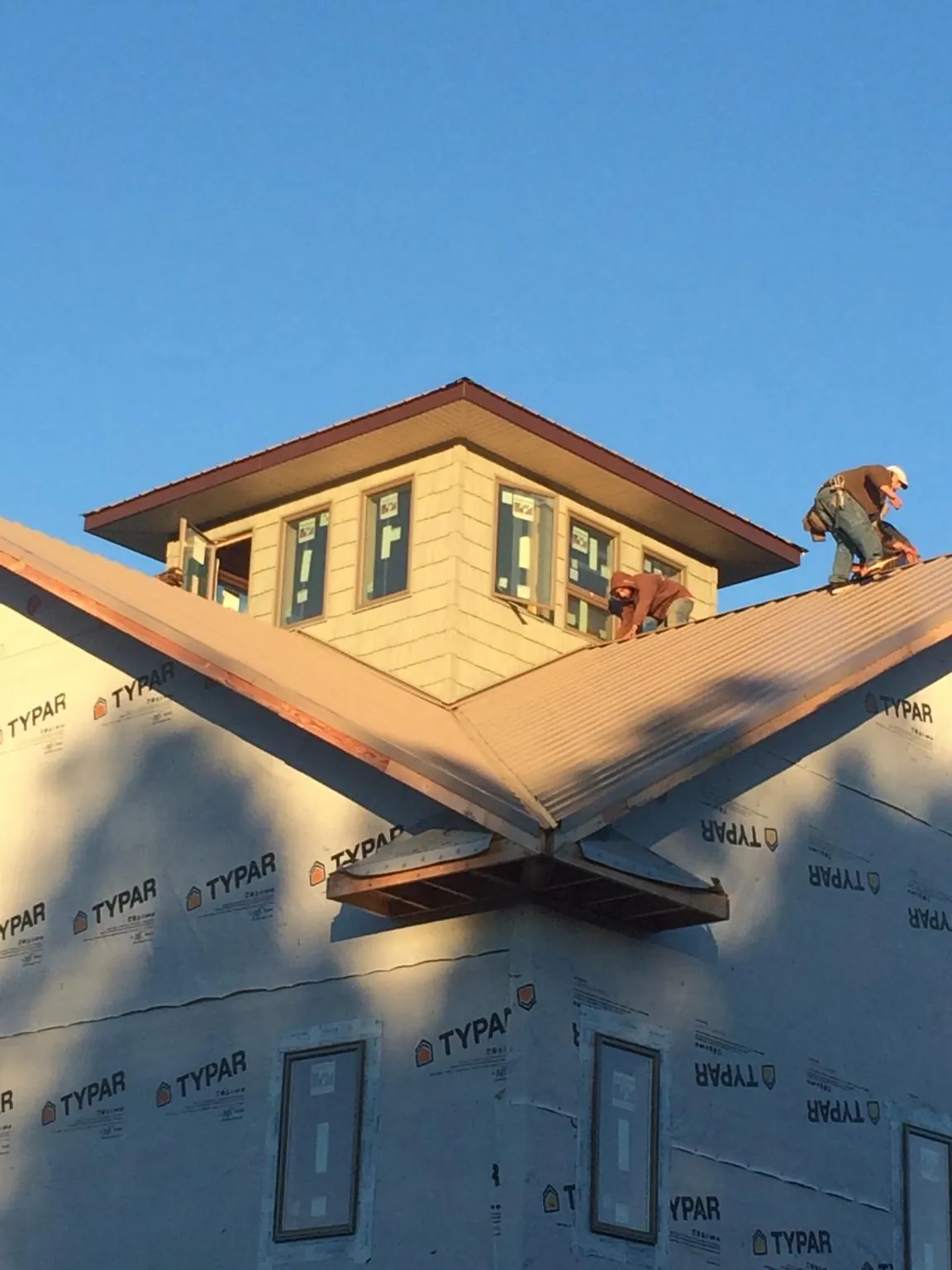 Roofers working around a rooftop cupola on a new metal roof at sunset — Roof Waterproofing in Cheswick by Roofing Brothers